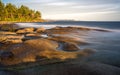 Long exposure shot of sea waves from a rocky shore with beautiful hills and trees in the background Royalty Free Stock Photo
