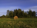 Long exposure shot of single round haystack in the meadow during summer evening, cattle fodder in countryside Royalty Free Stock Photo