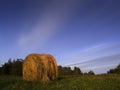 Long exposure shot of single round haystack in the meadow during summer golden hour at evening, cattle fodder in countryside Royalty Free Stock Photo