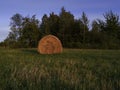 Long exposure shot of single round haystack in the meadow during summer golden hour at evening, cattle fodder in countryside Royalty Free Stock Photo