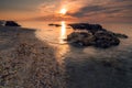 Long exposure shot to catch the moving waves on a beach near some rocks in the foreground againt the rising sun Royalty Free Stock Photo