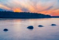 Long Exposure of Sunset at the Paijanne lake. Beautiful scape with stone beach, pine forest and water. Lake Paijanne, Finland