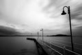 Long exposure view of a pier on a lake, with moving clouds and still water Royalty Free Stock Photo