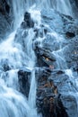 Long exposure waterfall crashes down on jagged black rocks. Royalty Free Stock Photo