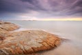 Long exposure of wave hitting rock during twilight with stunning