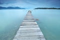 Long exposure of wooden jetty at sea facing island with cloud an