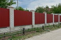 Long fence of red metal and white brick on the street