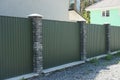 Long fence wall of green metal and gray bricks