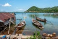 Long fishing boats in Thailand on the water next to the fisherman`s hut on stilts in the water. Royalty Free Stock Photo