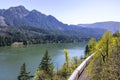 Long freight train travels by rail road along the Columbia River with forested mountains at Columbia Gorge Royalty Free Stock Photo