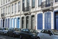 Long french building with blue shutters and row of cars