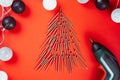 Long golden self-tapping screws, laid out in shape of Christmas tree, screwdriver and ball garland, on red background Royalty Free Stock Photo