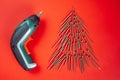 Long golden self-tapping screws, laid out in shape of Christmas tree, and screwdriver on red background Royalty Free Stock Photo