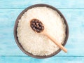 Long grain Basmati rice in ceramic bowl, allspice in wooden spoon on blue