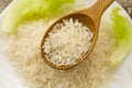 Long grain rice in a wooden spoon on a background plate, green salad. Healthy eating, diet