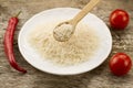 Long grain rice in a wooden spoon on a background plates, chili pepper, cherry tomato. Healthy eating, diet Royalty Free Stock Photo