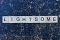 Long gray word lightsome from wooden letters in black font