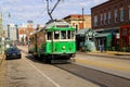 A long green and white electric cable car driving up a long street surrounded by red brick office buildings and skyscrapers Royalty Free Stock Photo