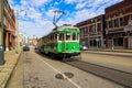 A long green and white electric cable car driving up a long street surrounded by red brick office buildings and skyscrapers Royalty Free Stock Photo