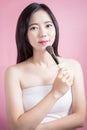Long hair asian young beautiful woman applying cosmetic powder brush on smooth face isolated over pink background. natural makeup. Royalty Free Stock Photo