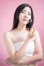 Long hair asian young beautiful woman applying cosmetic powder brush on smooth face isolated over pink background. natural makeup. Royalty Free Stock Photo