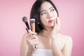 Long hair asian young beautiful woman applying cosmetic powder brush on smooth face isolated over pink background. natural makeup. Royalty Free Stock Photo