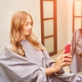 Long hair procedure at salon. Woman with smartphone. Adult female person