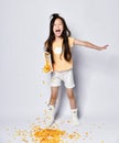 Long haired asian girl kid in home clothes singing screaming in the morning breakfast and poures out corn flakes on gray Royalty Free Stock Photo