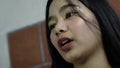 Long-haired beautiful Asian girl standing near the brick wall reciting homework narration lesson assignment.