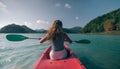 Long haired blonde woman with sunglasses rows bright pink canoe along sea bay water to beach with growing palms. Royalty Free Stock Photo