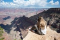 young girl sitting on the edge of the cliff of the Grand Canyon taking photos