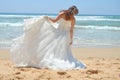 Long-haired brunette bride straightens her dress standing on the sand, the beach on the Indian Ocean. Wedding and honeymoon