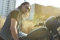 Long-haired brunette guy posing on a black custom motorcycle Royalty Free Stock Photo