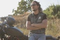 Long-haired brunette guy posing on a black custom motorcycle Royalty Free Stock Photo