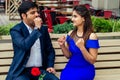 Long haired brunette indian woman in blue dress with her handsome boyfriend having dating getting bored .man giving rose Royalty Free Stock Photo