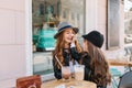 Long-haired brunette little girl gently touching mother`s face, sitting in outdoor cafe with glass of milk shake Royalty Free Stock Photo