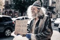 Long-haired desperate senior homeless wearing ragged clothes