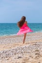 Girl in pink dress running along pebble beach Royalty Free Stock Photo