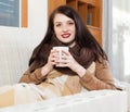 Long-haired girl with cup near calorifer Royalty Free Stock Photo