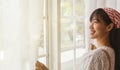 The long-haired girl opened the window curtain to see the morning sunlight in the living room, looking outside, smiling, good-humo Royalty Free Stock Photo