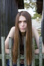 Long-haired girl stands near a wooden village fence. Royalty Free Stock Photo