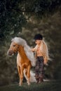 Little girl with palomino miniature horse in summer day Royalty Free Stock Photo