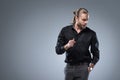 Long haired man in black shirt looking down with hand in pocket, isolated on gray Royalty Free Stock Photo