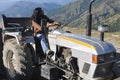 A long haired man looking sideways while driving an old tractor in hilly area Royalty Free Stock Photo