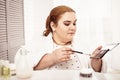 Long-haired plus-size woman coating her brush into eyeshadows