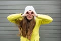 Long-haired stylish girl in a yellow coat and hat looks through binoculars. Invitation to the Journey to see the world Royalty Free Stock Photo