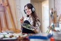 Long-haired woman in headphones paints with oil colors Royalty Free Stock Photo