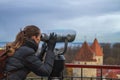 Long-haired woman tourist looking through binoculars historical sights of Tallinn city. Royalty Free Stock Photo