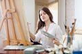 Long-haired young woman paints on canvas