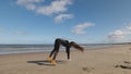 Long-haired young woman practices front and back handspring and cartwheel on beach with sea view. Slow motion